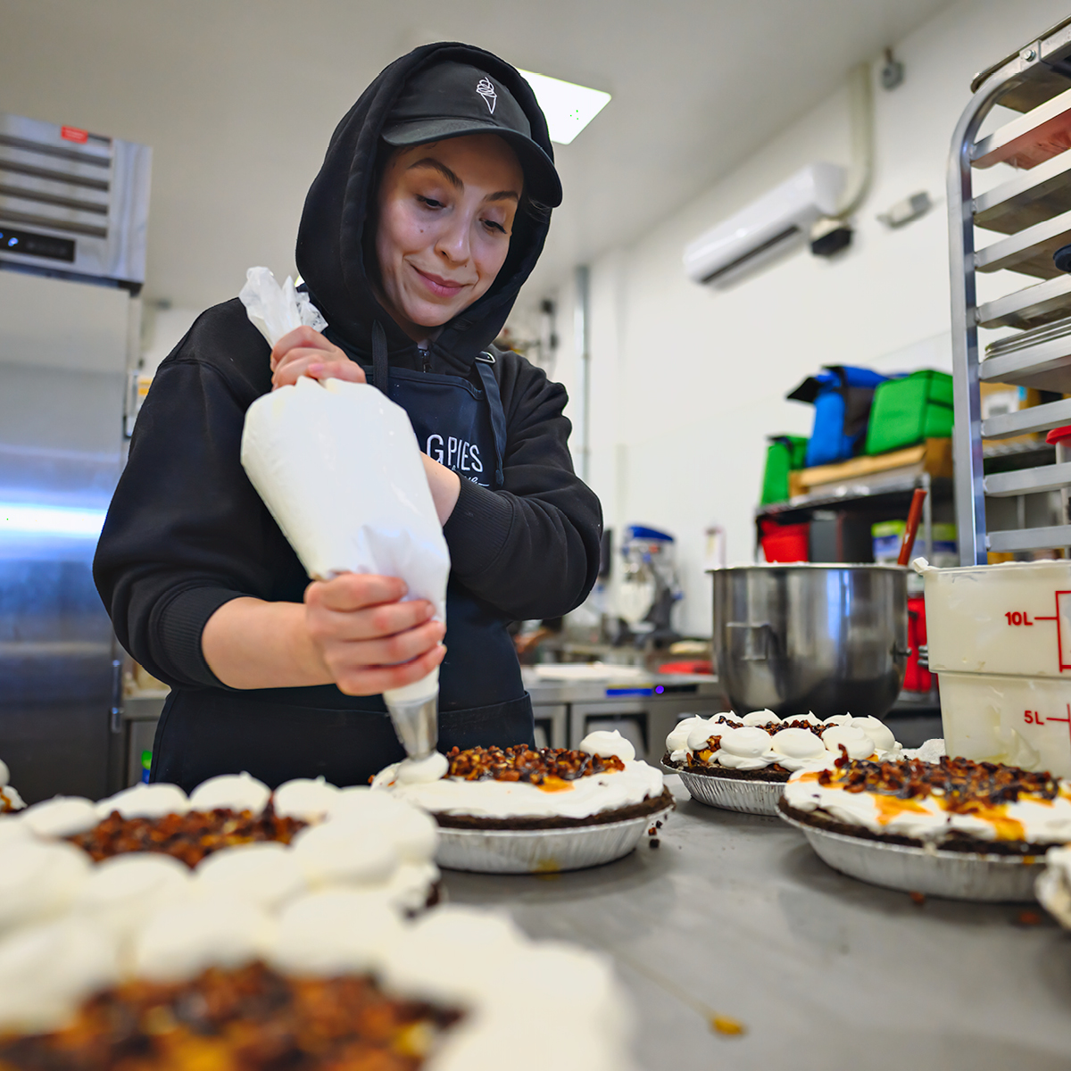 Staff piping whipped topping onto soft serve pies in the kitchen