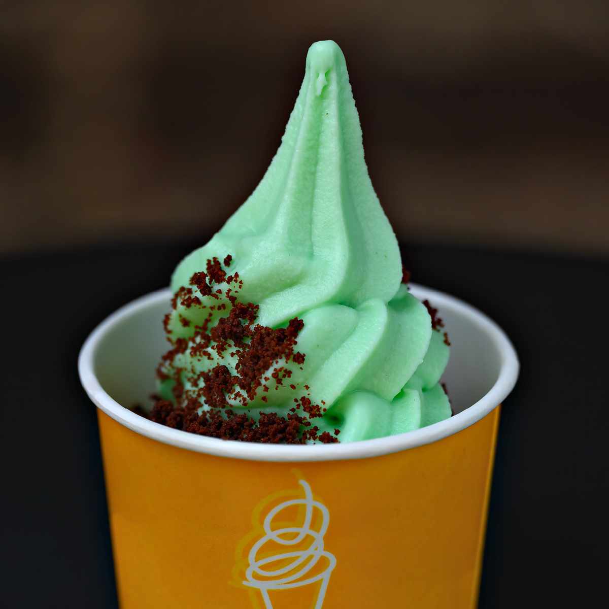 Mint soft serve ice cream in a paper cup with crumb topping
